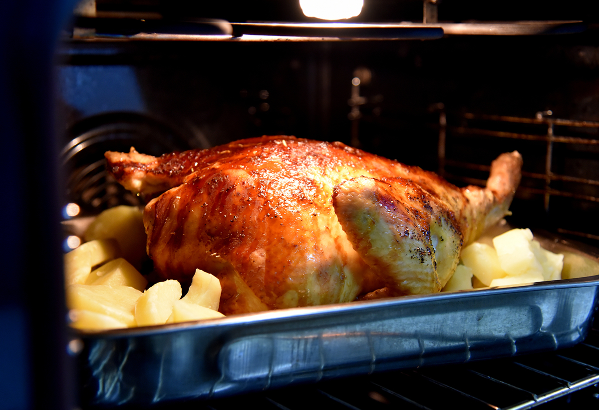 Απεικονίζεται ένα ταψί με κοτόπουλο το οποίο ψήνεται στον φούρνο.
